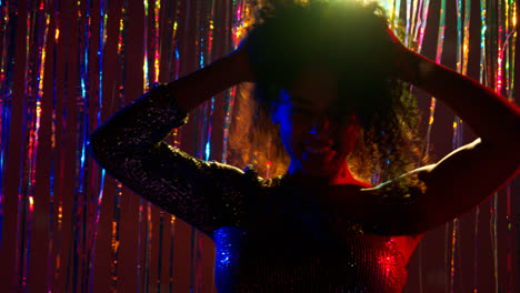 Portrait-Of-Young-Woman-Having-Fun-In-Nightclub-Or-Bar-Dancing-Against-Sparkling-Tinsel-Curtain-in-Background